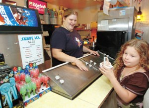electing a snack at the Holiday Drive-In concession stand isn’t easy because of the myriad of choices available, but Emily Philpott seems satisfied with her cup of ice cream served up by grill cook Amber Ridener from behind the counter. Emily, 8, is from Bedford. Drive-in theaters make most of their money to stay in business not from ticket sales but from sales at the snack bar. Holiday Drive-In, located along Ind. 37 between Mitchell and Orleans and surrounded by rolling farm fields, is served electrically by Orange County REMC.