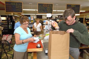 Andrew Gilleo bags items for Kathy Kuss as she writes a check. Kuss is an Orange County REMC conumer who frequents the market and deli.