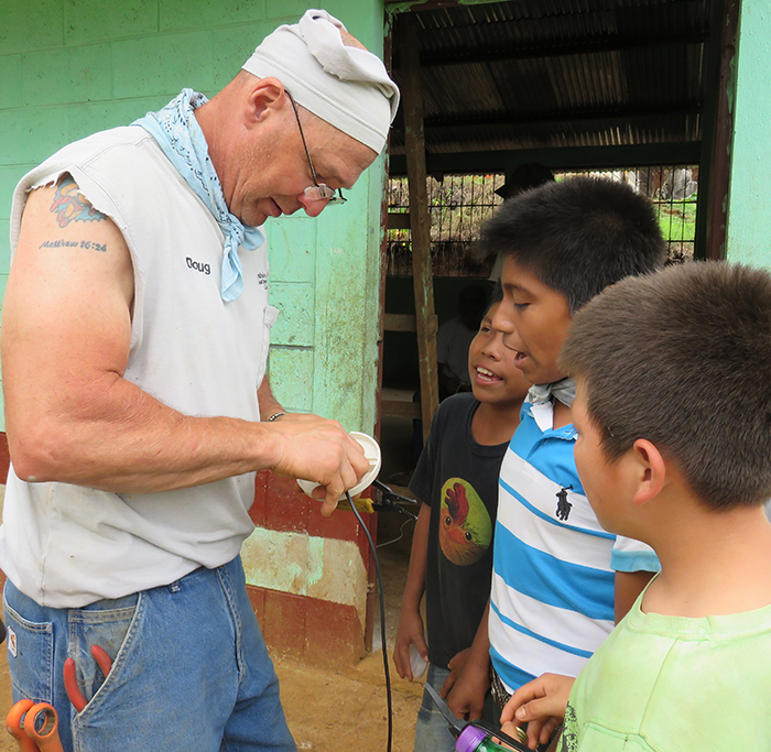 Doug MacLain, Marshall County REMC, shows boys in the village how to wire a light socket.