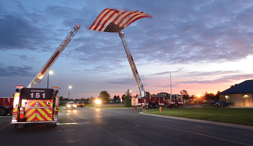 5:55 am: Honor Flight participants arrive at the 122nd Fighter Wing Air National Guard Base in Fort Wayne May 20 to begin their day, passing under a large flag hoisted by the Southwest Allen County Fire District.
