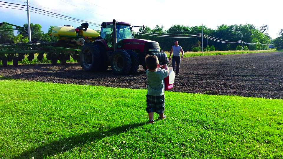 Silas Shake carries supper to  his dad, Lucas Shake, in their field  in Linton, Indiana.