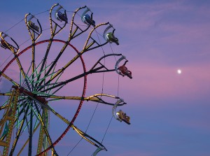 Ferris wheel against a dusky blue and pink sky with rising full moon