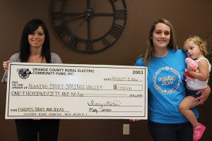 Running Start — Springs Valley received an Operation Round Up® grant for $1,050 to purchase T-shirts, socks and shoes. Pictured at left are REMC Member Service Representative Lorena Lindsey with Jennifer Hill and baby Evelyn, accepting the grant on behalf of Running Start.