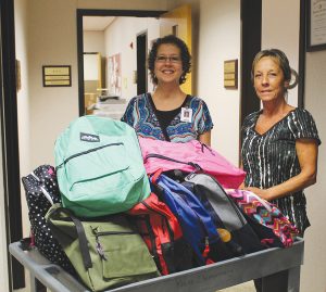 Kouts Elementary School Principal Patti Eich and Secretary Sheila Sutter accept backpacks that will support students in their school system.
