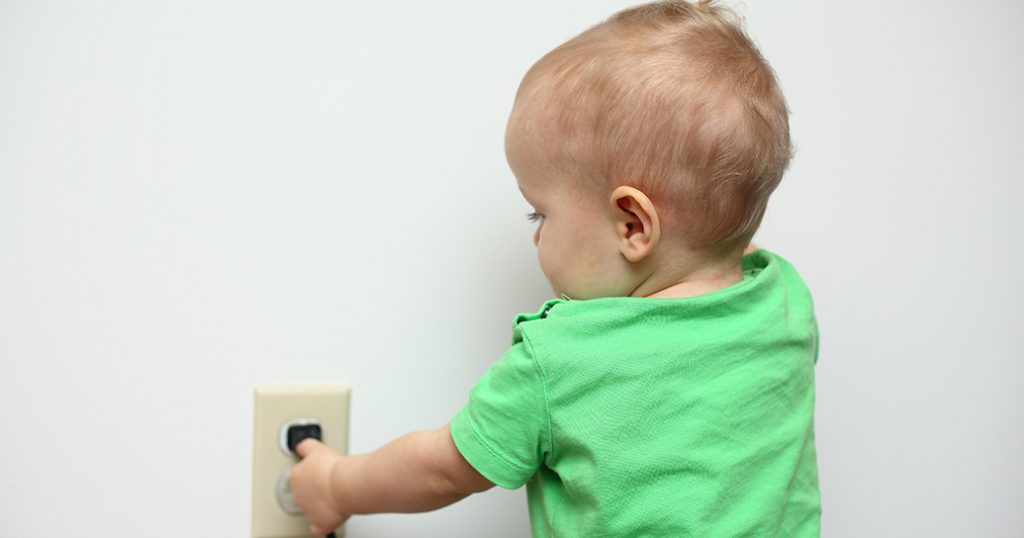 Toddler playing with electrical outlet