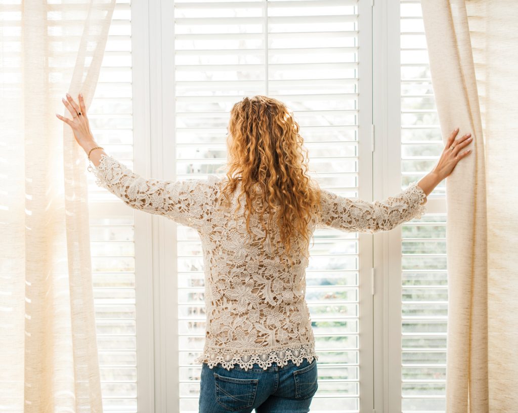 Woman opening curtains