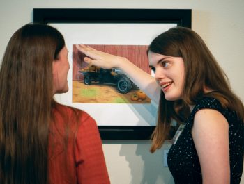 2020 art contest winner Danielle Sommerman showing her art to a guest