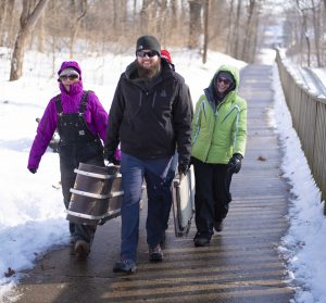 Group carrying toboggans in winter weather gear.