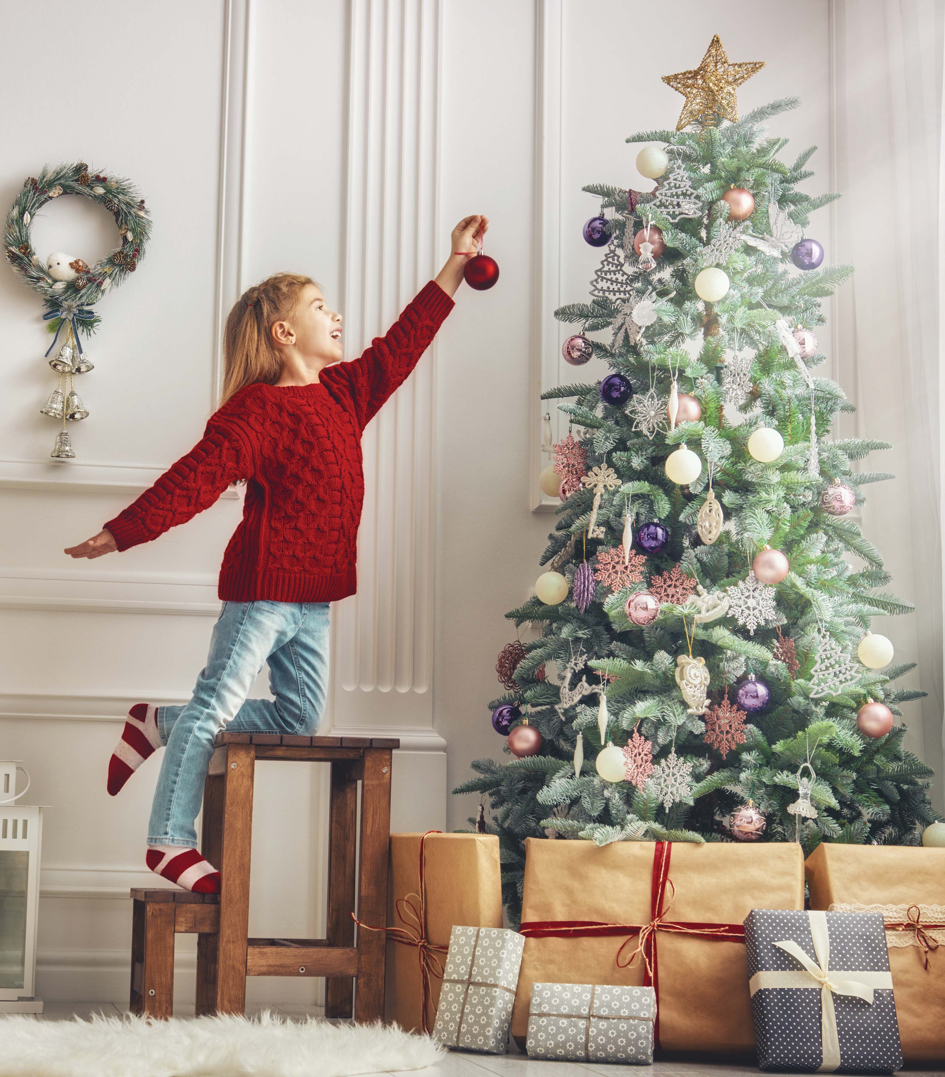 Girl placing Christmas ornament on a tree