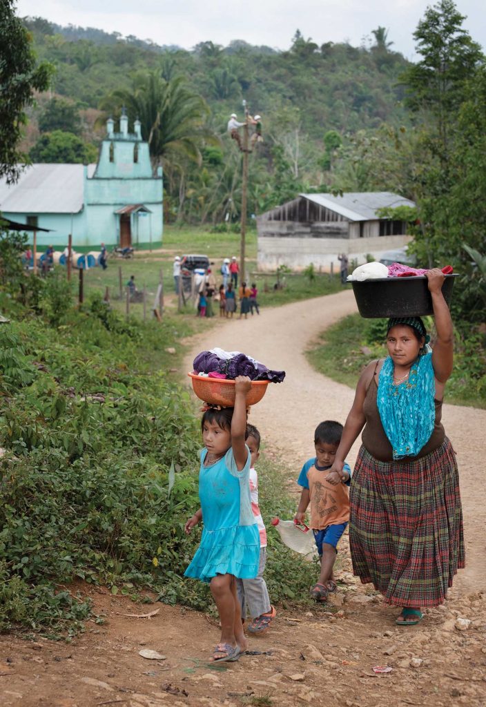 Guatemalan woman and family carrying supplies to their home on their heads.