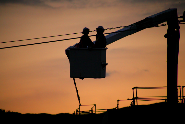 Two men in a bucket lift working on power lines