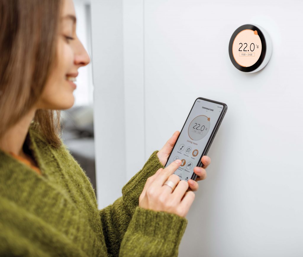 Woman controlling thermostat with smartphone