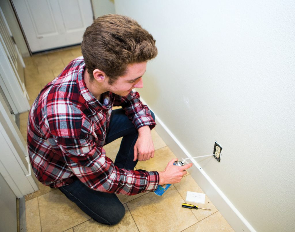 Photo of man sealing air leaks around an outlet