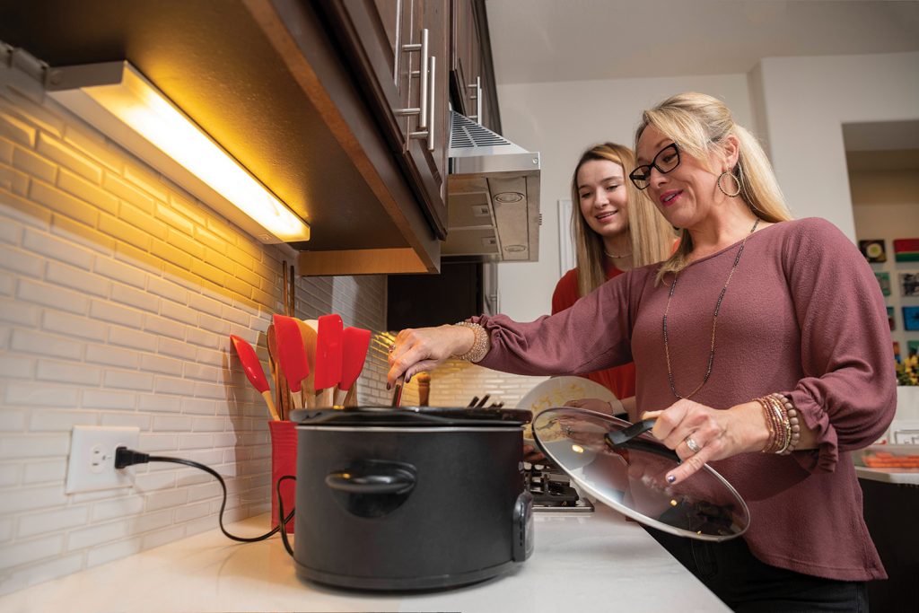 Mother and daughter cooking using slow cooiker