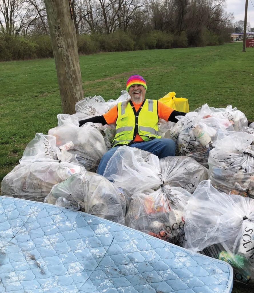 Man surrounded by trash bags.