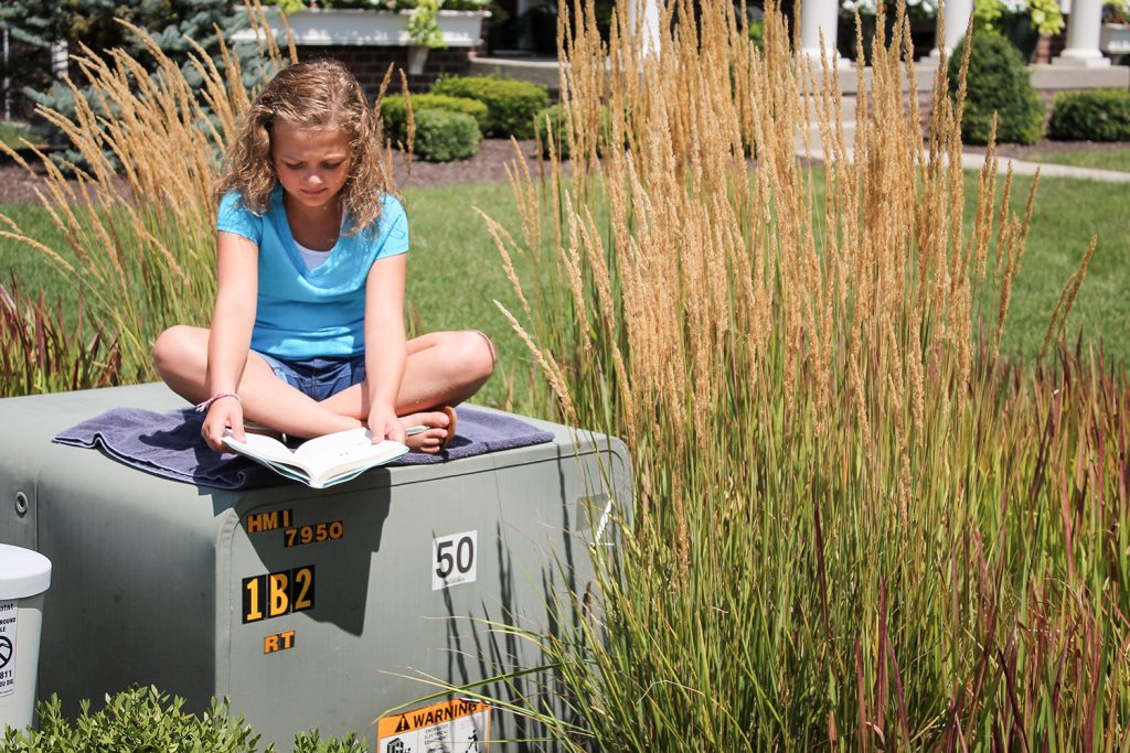 Girl reading on top of a pad-mount transformer