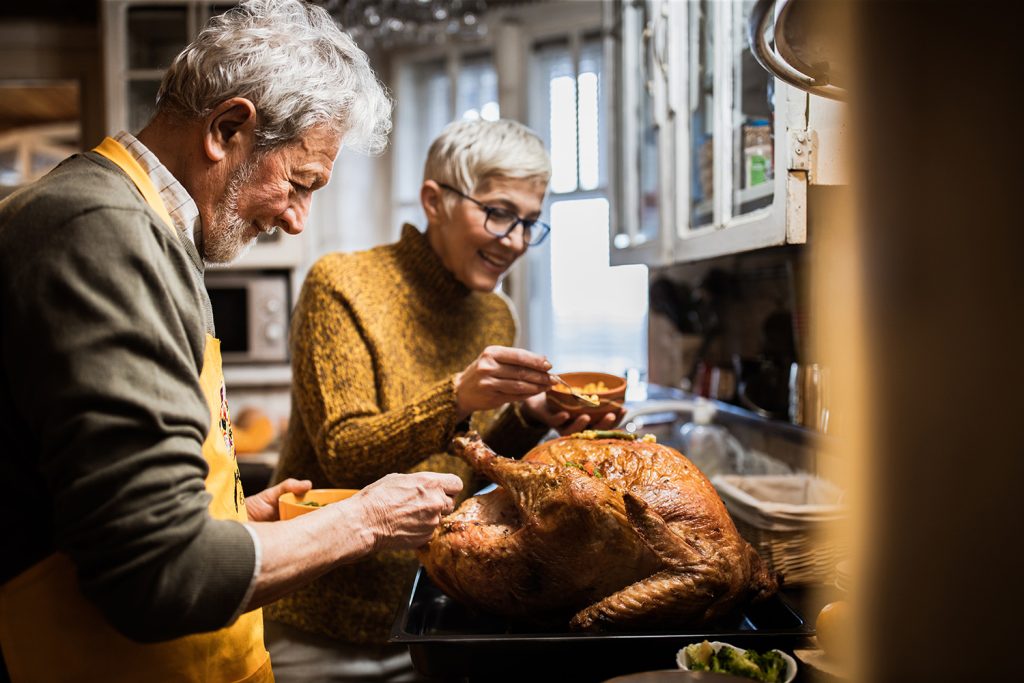 Grandparents in kitchen cooking turkey