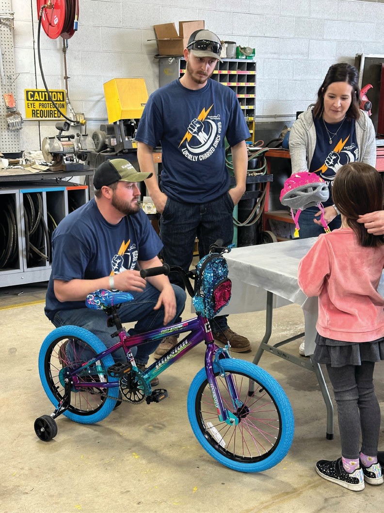 KV REMC employees present their finished bike to a student.