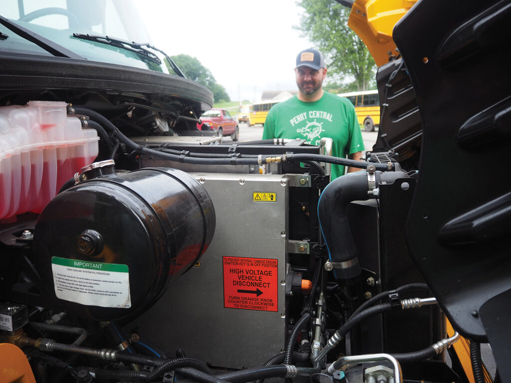 Bus driver Nathan Toothman checks the engine of the new EV bus.