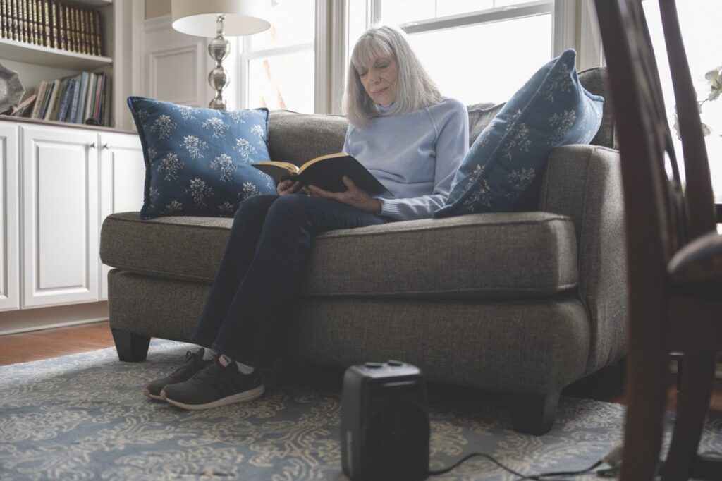 Woman reading a book on the couch with space heater