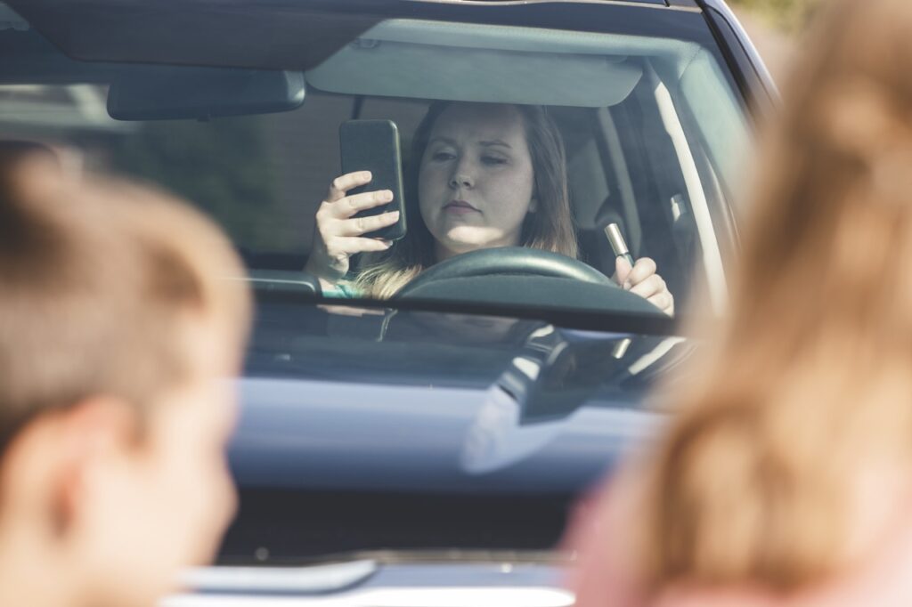 Distracted driver is texting and doing her makeup, almost hitting children in the crosswalk